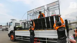Relawan Dompet Dhuafa memasang tangga untuk masyarakat yang akan menggunakan disinfektan chamber di CheCk Point PSBB, perbatasan Jakarta - Tangsel, Pasar Jumat, Kamis (16/4/2020). Keberadaan bilik tersebut untuk memutus rantai penyebaran Corona COVID-19. (Liputan6.com/Fery Pradolo)
