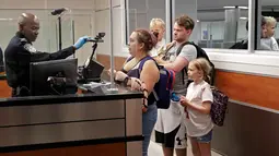 Petugas bea cukai menyesuaikan kamera pemindaian wajah ke sebuah keluarga di Bandara Internasional Orlando, Florida, Kamis (21/6). Ketentuan ini berlaku untuk semua penumpang yang tiba dan berangkat menggunakan penerbangan internasional. (AP/John Raoux)