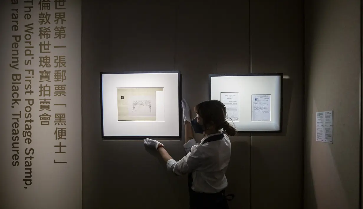 Petugas memegang bingkai dengan prangko pertama di dunia, Penny Black, menjelang pelelangannya, di Sotheby Hong Kong, Selasa (26/10/2021). Prangko ini pertama kali diterbitkan di Britania Raya pada tanggal 1 Mei 1840, tetapi baru digunakan secara resmi tanggal 6 Mei. (ISAAC LAWRENCE / AFP)