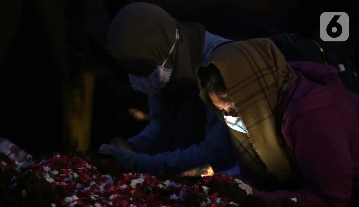 Kerabat berdoa di sisi makam jenazah dengan protokol Covid-19 di TPU Rorotan, Jakarta, Rabu (23/6/2021). Gubernur Provinsi DKI Jakarta Anies Baswedan mengatakan, hingga Rabu (23/6) 900 jenazah dimakamkam dengan protokol Covid-19 di TPU Rorotan.  (Lipiutan6.com/Helmi Fithriansyah)