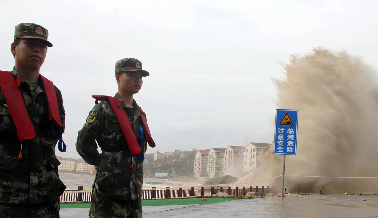 Paramiliter China berjaga-jaga saat ombak besar yang diakibatkan terpaan Topan Maria menghantam pantai dekat Wenling di Provinsi Zhejiang, China, Rabu (11/7). (AFP)