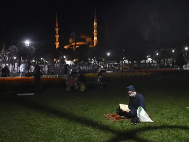 Seorang pemuda membaca dari Al-Quran sehari sebelum salat Jumat pertama di monumen tengara dalam 86 tahun setelah konversi kembali ke masjid di luar dirinya era-Bizantium Hagia Sophia, di distrik bersejarah Sultanahmet Istanbul, Kamis, (23/7/2020). (AP Photo/Omer Kuscu)