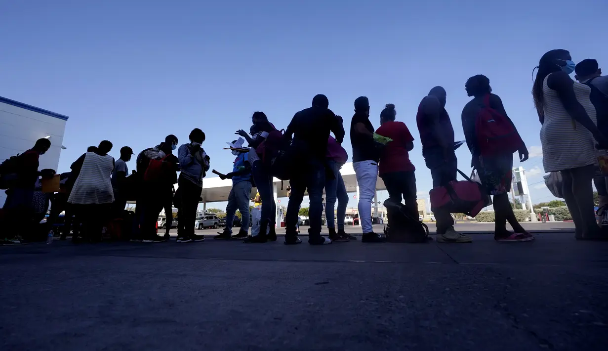 Para Migran Haiti menunggu bus setelah diproses di kamp darurat di Del Rio, Texas, Minggu (19/9/2021). Pemerintahan Presiden Joe Biden mendekati final berencana untuk mengusir ribuan migran Haiti yang tiba-tiba menyeberang ke kota perbatasan Texas dari Meksiko. (AP Photo/Eric Gay)
