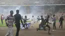Pihak keamanan stadion pun membalas ulah suporter dengan menembakkan gas air mata untuk memukul balik para suporter. (AP/Sunday Alamba)