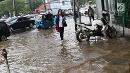 Pejalan kaki melintasi banjir yang merendam kawasan Gambir, Jakarta, Kamis (15/2). Banjir tersebut mengakibatkan jalan di sekitar lokasi terpaksa ditutup karena tidak bisa dilalui kendaraan bermotor. (Liputan6.com/Immanuel Antonius)