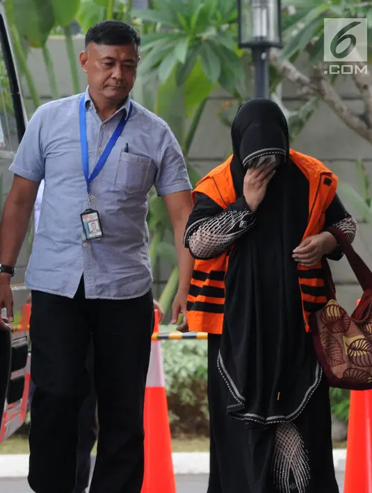 Anggota DPRD Kota Malang Een Ambarsari (kanan) menutupi wajah saat tiba di Gedung KPK, Jakarta, Selasa (2/10). Een menjalani pemeriksaan terkait dugaan menerima suap pembahasan APBD-P Pemkot Malang Tahun Anggaran 2015. (Merdeka.com/Dwi Narwoko)