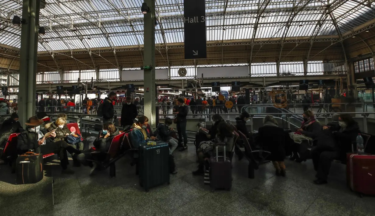 Orang-orang yang memakai masker menunggu dengan barang bawaan mereka di stasiun kereta Gare de Lyon di Paris, Jumat (19/3/2021). Prancis menerapkan karantina wilayah di Paris dan beberapa daerah lain di bagian utara selama sebulan dan dimulai pada Jumat tengah malam. (AP Photo/Michel Euler)