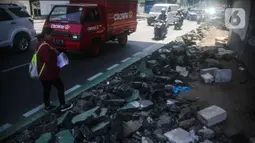 Pejalan kaki melintas di samping jalur sepeda yang di bongkar di kawasan Cikini, Jakarta, Selasa (19/11/2019). Jalur sepeda berumur 2 bulan tersebut dibongkar akibat proyek pelebaran trotoar. (Liputan6.com/Faizal Fanani)