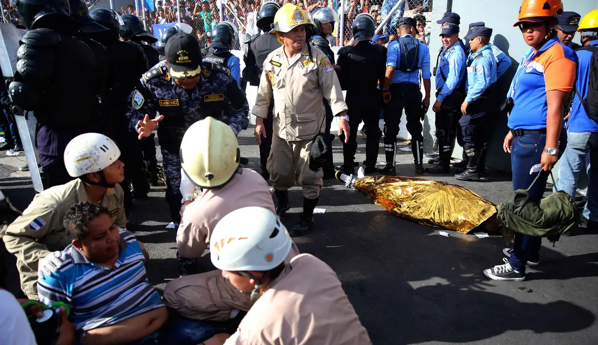Petugas mengevakuasi korban kericuhan dalam Pertandingan final antara Motagua kontra Progreso di kota Tegucigalpa, Honduras (28/5). Pertandingan tersebut berjalan ricuh sehingga mengakibatkan empat orang meregang nyawa. (AP Photo/Fernando Antonio)