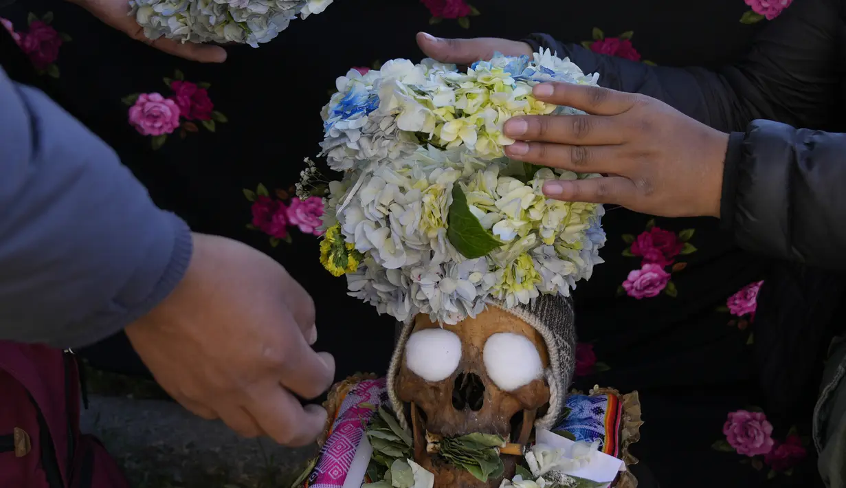 Orang-orang menghias tengkorak manusia dengan bunga di pemakaman umum selama festival tahunan "Natitas" di La Paz, Bolivia, Senin (8/11/2021). Dalam festival ini warga ramai-ramai menghias tengkorak leluhur mereka dengan berbagai dekorasi mulai dari bunga, topi hingga kacamata (AP Photo/Juan Karita)