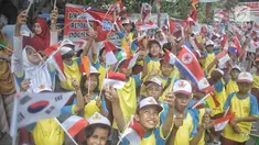 Siswa-siswi SD membawa bendera negara peserta Asian Games 2018 untuk menyambut Kirab Obor di kawasan Jati Padang, Pasar Minggu, Rabu (15/8). Mereka memenuhi jalanan untuk menyaksikan langsung Pawai Obor Asian Games 2018. (Liputan6.com/Faizal Fanani)