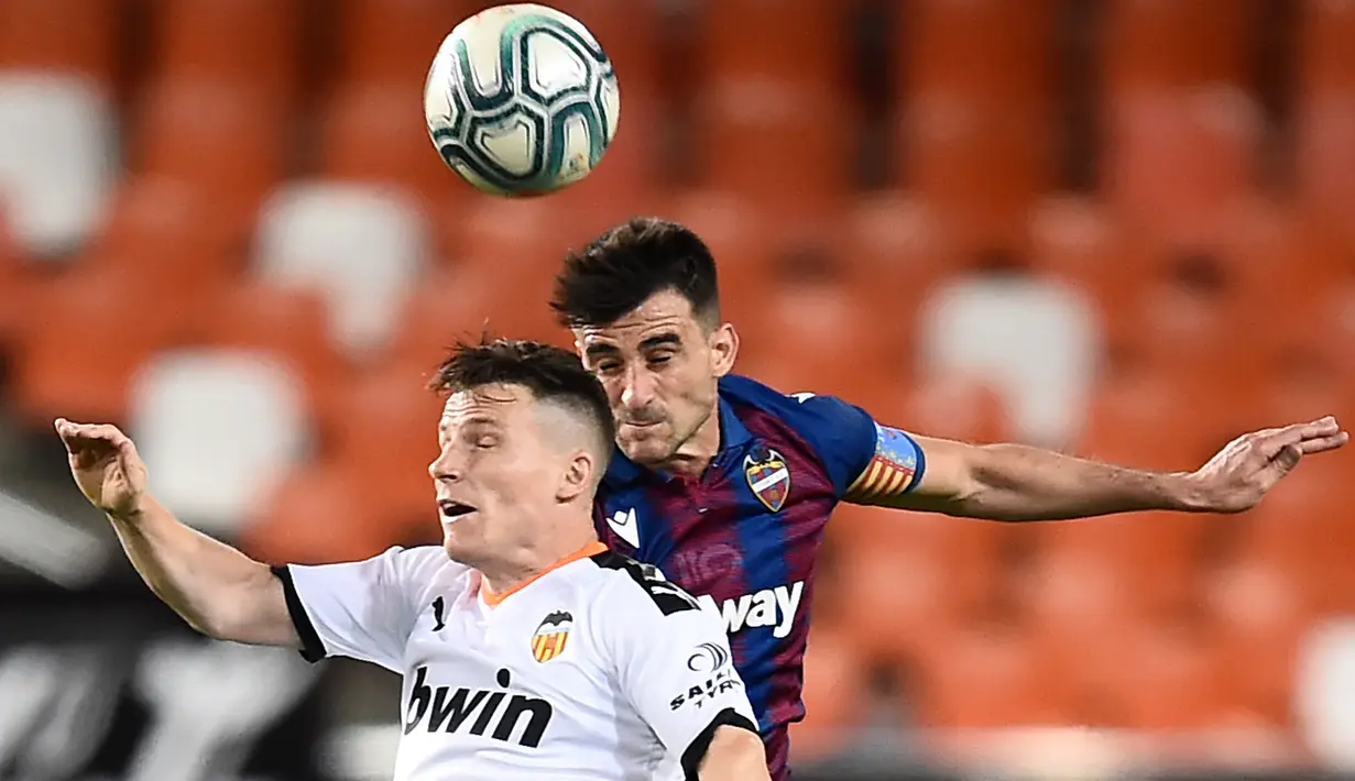 Penyerang Valencia, Kevin Gameiro, berebut bola dengan bek Levante, Sergio Postigo, pada laga pekan ke-28 Liga Spanyol di Stadion Mestalla, Sabtu (13/6/2020) dini hari WIB. Valencia bermain imbang 1-1 atas Levante. (AFP/Jose Jordan)