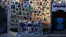 Seorang wanita duduk didepan dinding yang dihiasi dengan mosaik di desa Jaimanitas, Havana, Kuba, (14/7). Fuster juga menghiasi desanya dengan lukisan Picasso. (REUTERS / Enrique de la Osa)