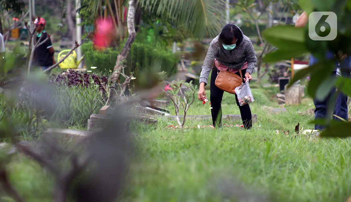 Peziarah menabur kembang di salah satu makam di Tempat Pemakaman Umum Karet Bivak, Jakarta, Sabtu (18/4/2020). Selama masa PSBB, peziarah yang memasuki kawasan TPU dibatasi dan diwajibkan menggunakan masker sebagai langkah pencegahan penyebaran virus Covid-19. (Liputan6.com/Helmi Fithriansyah)