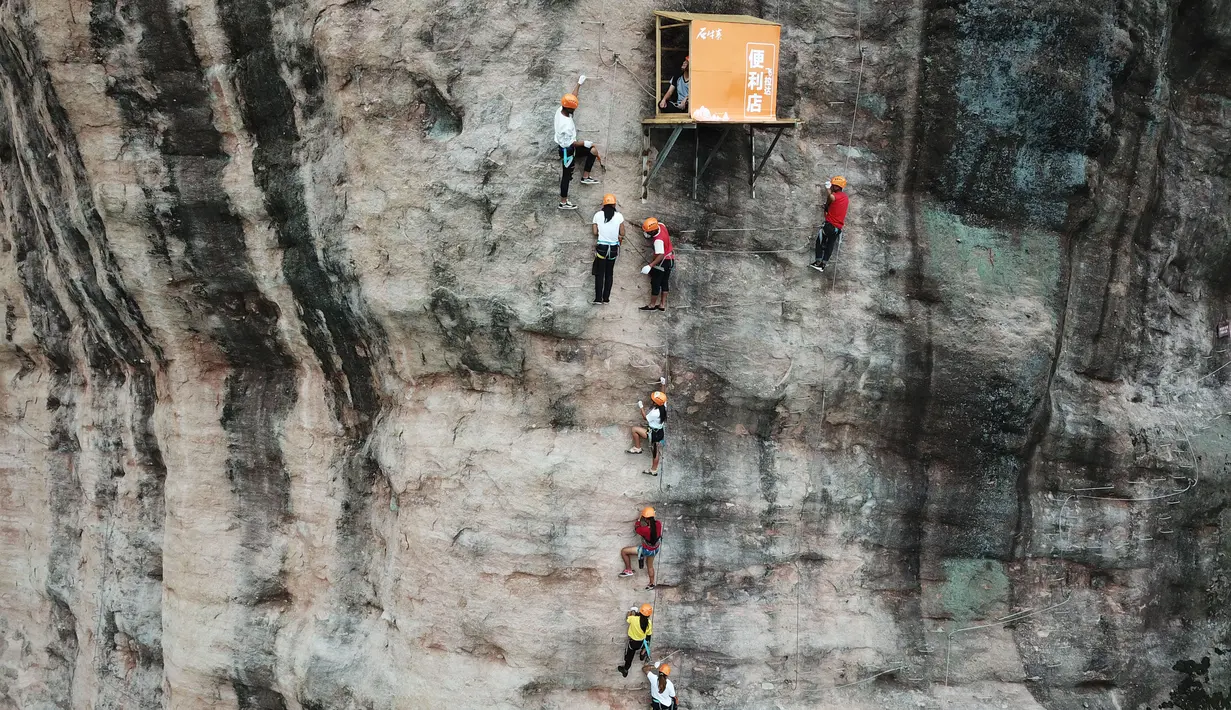 Sejumlah orang melakukan panjat tebing di Pingjiang di provinsi Hunan, China (25/4). Uniknya, di lintasan panjat tebing ini ada sebuah kotak yang merupakan toko atau warung yang menempel di dinding tebing. (AFP Photo/China Out)