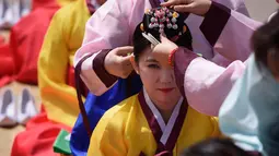 Seorang wanita muda melakukan ritual penyematan ornamen kepala selama upacara “Coming of Age” di Namsan Hanok Village, Seoul, Senin (20/5/2019). Di Korea Selatan, Coming of Age Day atau hari kedewasaan dirayakan secara nasional setiap tahun pada hari Senin ketiga di bulan Mei. (Ed JONES/AFP)