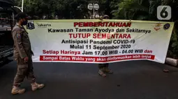 Petugas memasang spanduk pemberitahuan penutupan area kawasan Taman Ayodya, Jalan Bulungan dan Mahakam, Jakarta, Rabu (23/9/2020). Penutupan jalan dilakukan agar masyarakat tidak berkumpul di area itu pada waktu malam hari dan guna menekan angka penularan COVID-19. (Liputan6.com/Johan Tallo)