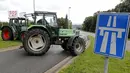 Sebuah traktor milik peternak sapi perah memblokade jalan tol atau jalan bebas hambatan saat melakukan aksi protes di Battice, Belgia, Kamis (30/7/2015). Aksi protes tersebut berkaitan dengan rendahnya harga jual susu. (REUTERS/Francois Lenoir)