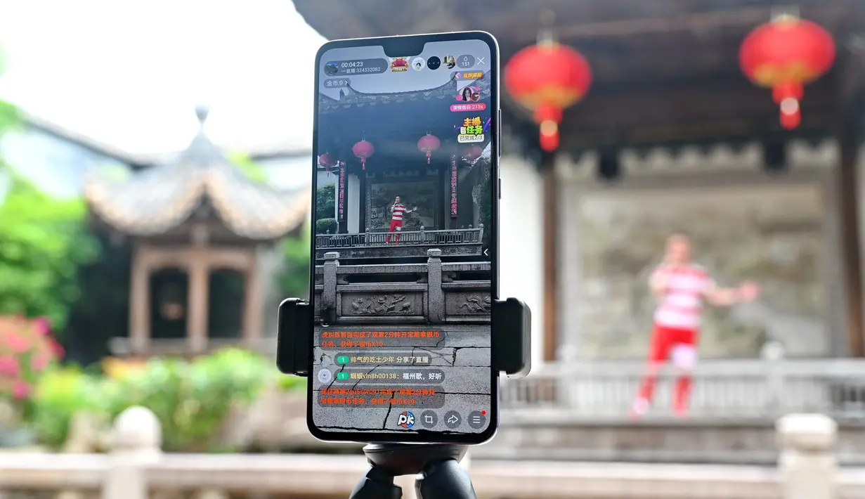 Seorang staf tampil livestreaming melalui ponsel di kawasan sejarah dan budaya di Fuzhou, Provinsi Fujian, China (19/5/2020). Otoritas setempat melakukan livestreaming melalui ponsel untuk memungkinkan masyarakat di mana pun untuk menikmati keindahan budaya lokal. (Xinhua/Lin Shanchuan)