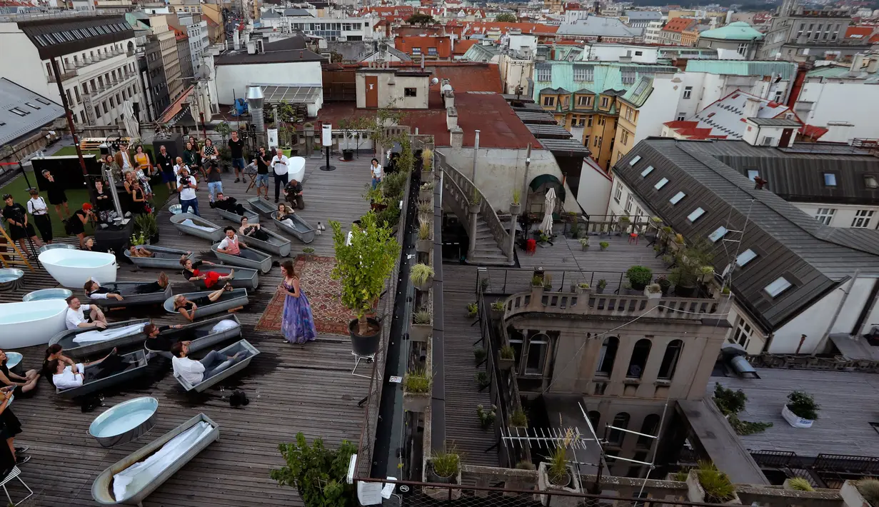 Penonton berendam dalam bak mandi sambil menyaksikan penyanyi opera Eva Kyvalova membawakan Don Giovanni karya Mozart di atap Gedung Lucerna, Praha, Republik Ceko, Kamis (29/8/2019). (AP Photo/Petr David Josek)