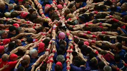 Kompetisi Taragon Castells terinspirasi dari kegiatan kelompok penari pada abad ke-18, Spanyol, Sabtu (1/10). Tim dinyatakan menang apabila berhasil membuat menara manusia yang tertinggi. (AFP PHOTO / Lluis Gene)