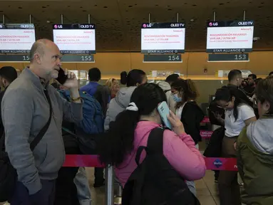 Para penumpang Ultra Air mengantre di konter maskapai penerbangan Avianca untuk terbang siaga secara gratis setelah maskapai penerbangan mereka, Ultra Air, menangguhkan operasinya, di Bandara Internasional El Dorado di Bogota, Kolombia, Kamis (30/3/2023). (AP Photo/Fernando Vergara)