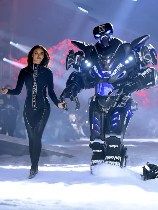Model Irina Shayk bersandingan dengan robot saat mengenakan koleksi desainer Philipp Plein dalam New York Fashion Week 2018, Sabtu (10/2). Irina menggunakan bodysuit hitam ketat yang mempertegas tubuh seksinya. (Dimitrios Kambouris/GETTY IMAGES/AFP)