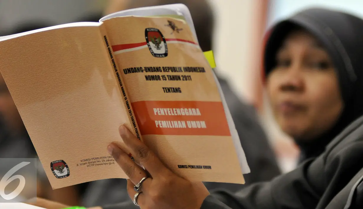 Anggota KPU membaca buku Undang-Undang tentang Penyelenggaraan Pemilihan Umum saat menghadiri acara Uji Publik Pilkada Serentak 2017 di Gedung KPU, Jakarta, Senin (18/7). (Liputan6.com/Johan Tallo)