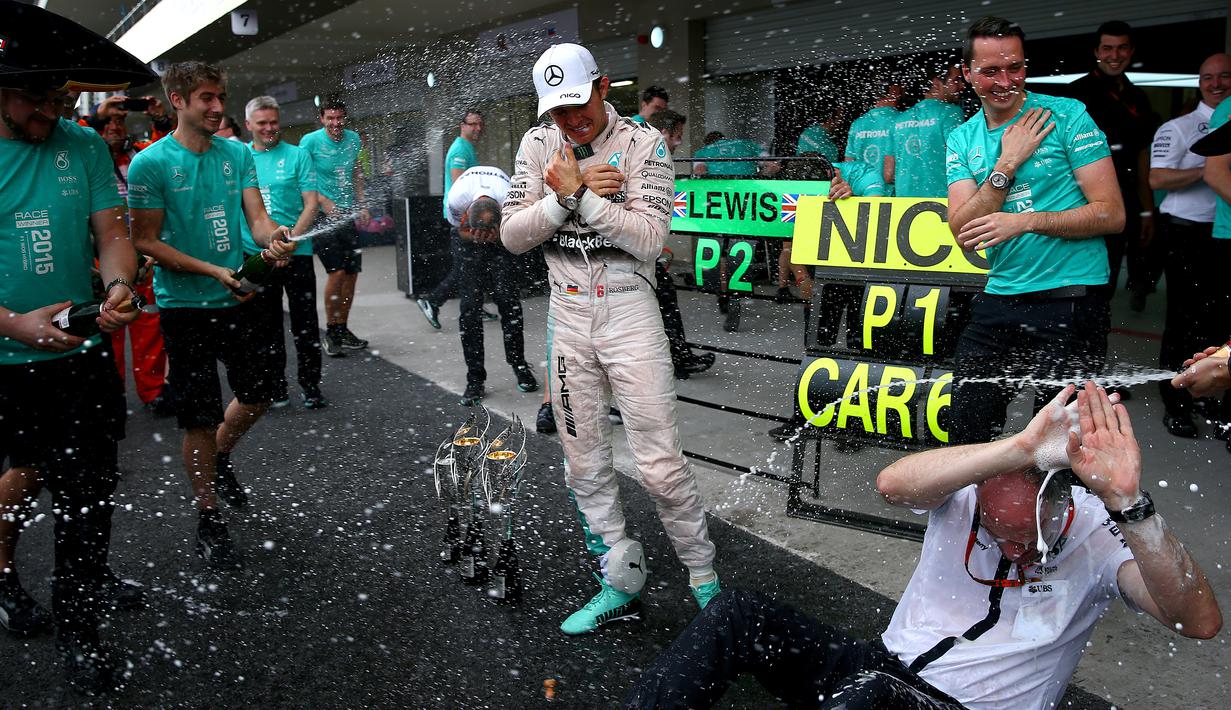 Anggota tim Mercedes menyemprotkan sampanye ke arah Nico Rosberg setelah menjuarai F1 GP Meksiko di Sirkuit Autodromo Hermanos Rodriguez, Senin (2/11/2015) dini hari WIB. (Getty Images/AFP/Mark Thompson)