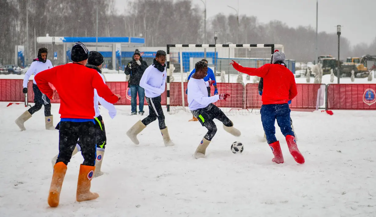 Para pemain berebut bola saat pertandingan persahabatan antara wartawan dan mahasiswa asing di lapangan bersalju di Nizhny Novgorod, Rusia, Minggu (21/1). Dalam pertandingan ini para pemain mengenakan sepatu tradisional Rusia. (AFP PHOTO/Mladen ANTONOV)