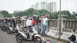 Pengendara sepeda motor mengamati banjir yang menggenangi kawasan Rawajati dari atas flyover di Jakarta Timur, Rabu (1/1/2020). Banjir yang berasal dari luapan Sungai Ciliwung itu menjadi daya tarik tersendiri bagi sebagian pemotor yang melintasi di flyover tersebut. (Liputan6.com/Immanuel Antonius)