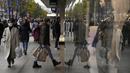 Seorang wanita tercermin saat berjalan ke sebuah toko di Oxford Street di London, Senin (29/11/2021). Di Inggris, kewajiban mengenakan masker akan berlaku lagi di toko-toko dan transportasi umum mulai Selasa menyusul temuan Covid-19 varian Omicron. (AP Photo/Matt Dunham)