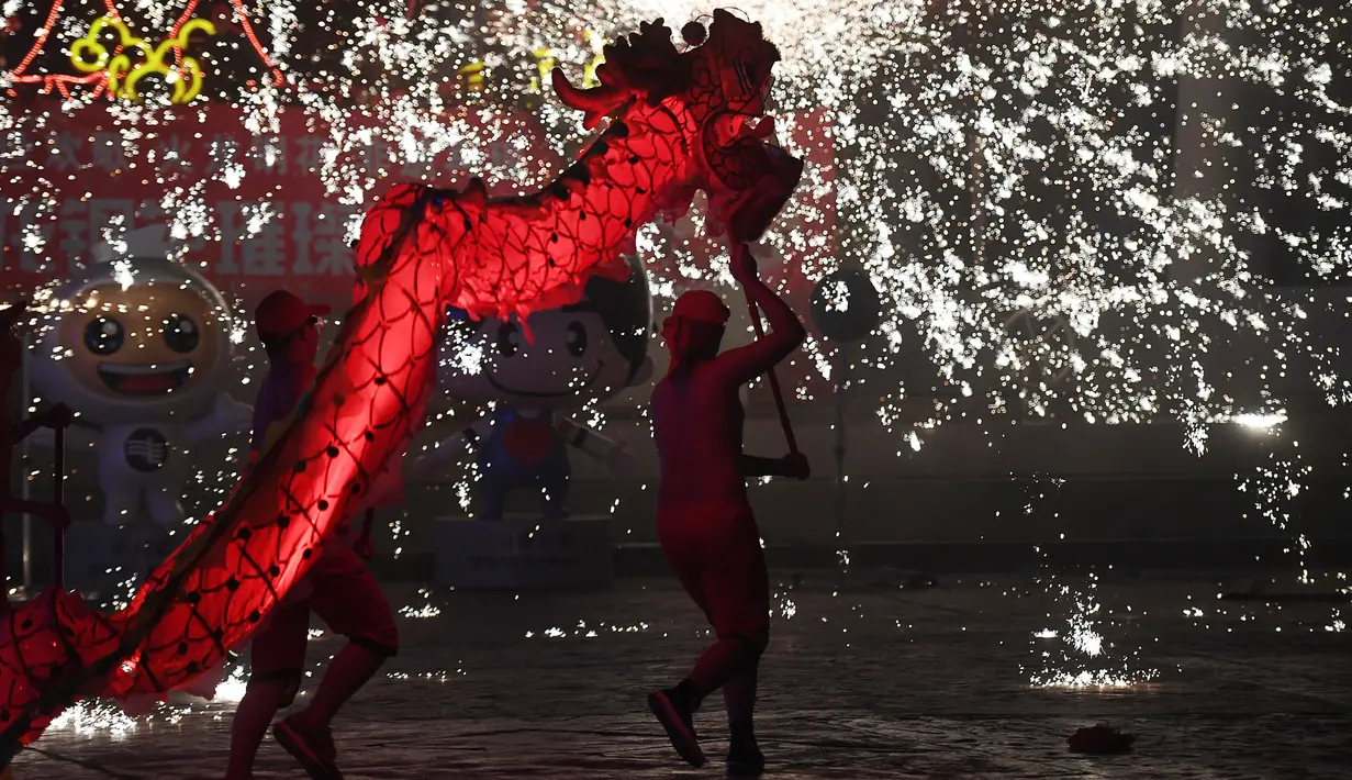 Penari melakukan tarian naga di sebuah taman pada hari keempat Tahun Baru Imlek di Beijing (8/2). China menandai kedatangan Tahun Babi dengan liburan Festival Musim Semi selama seminggu. (AFP Photo/Greg Baker)