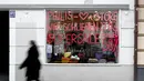 Seorang wanita melewati jendela toko yang bertuliskan 'Kami akan tutup pada 27 Maret' di Munich, Jerman, Selasa (23/3/2021). Jerman memperpanjang tindakan pengunciannya sebulan lagi. (AP Photo/Matthias Schrader)