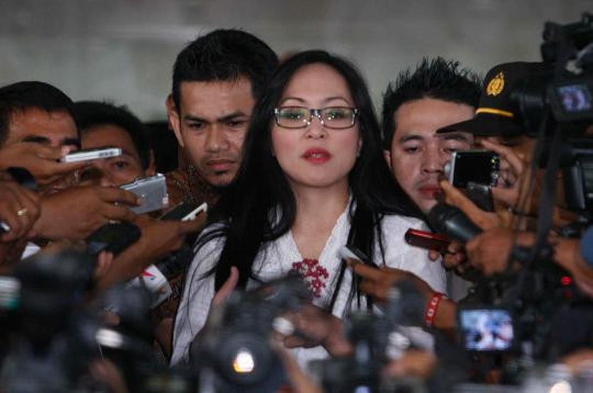Angelina Sondakh tersenyum saat dikawal petugas keamanan KPK dan polis 