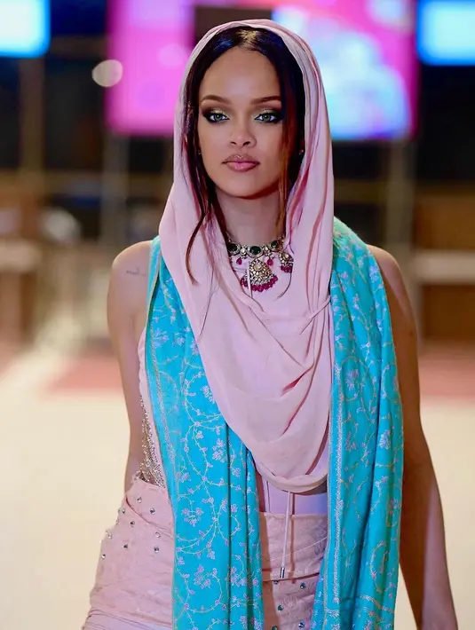 Usai after party, Rihanna bergegas meninggalkan India. Ia tampil memukau dalam balutan saree berwarna pink saat tiba di bandara menuju negara asalnya. Rihanna mengenakan sari merah muda dengan tudung dan dia juga mengenakan syal pirus. [@nounouche.online/@rihannadaily]