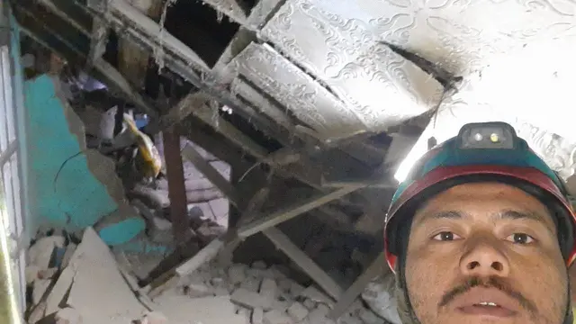 Seorang petugas Tagana Kab. Garut, Jawa Barat tengah memberikan pertolongan di salah satu rumah warga di Kampung Sukarasa Kecamatan Samarang, Garut setelag gempa 4,3 magnitudo, Rabu malam. (Liputan6.com/Jayadi Supriadin)