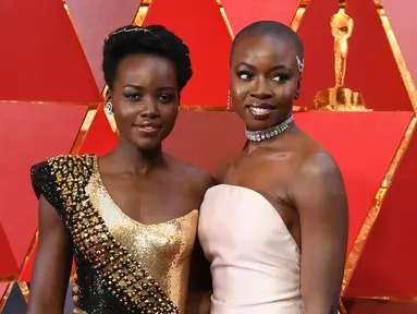 Aktris Kenya, Lupita Nyong'o dan aktris AS, Danai Gurira berpose untuk fotografer di karpet merah ajang Piala Oscar 2018, Los Angeles, Minggu (4/3).  Dua pemain "Black Panther" tersebut adu cantik mengenakan gaun seksi dan elegan. (ANGELA WEISS / AFP)