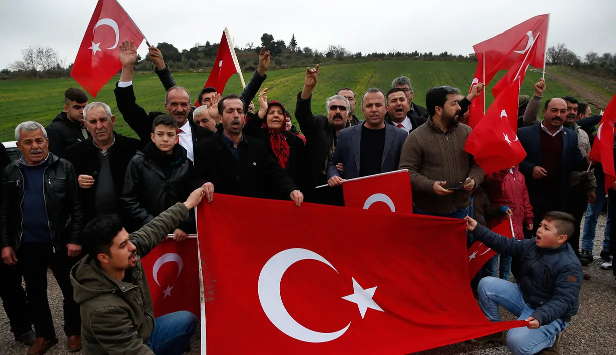 Warga membentangkan bendera sebagai dukungannya terhadap tentara Turki yang sedang memerangi milisi Kurdi di Suriah, Kilis, Turki, Jumat (26/1).  Pasukan Demokratik Suriah mengatakan serangan Turki telah menewaskan 100 orang. (AP Photo/Lefteris Pitarakis)