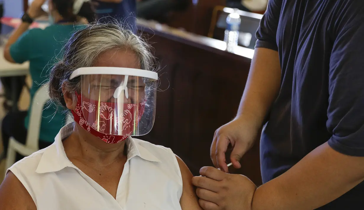 Reaksi seorang perempuan saat diinokulasi dengan vaksin COVID-19 produksi AstraZeneca di dalam gereja Paroki Hati Kudus Yesus di Quezon City, Filipina, Senin (17/5/2021). Gereja itu digunakan untuk mempercepat proses vaksinasi kepada warga di daerah tersebut. (AP Photo/Aaron Favila)