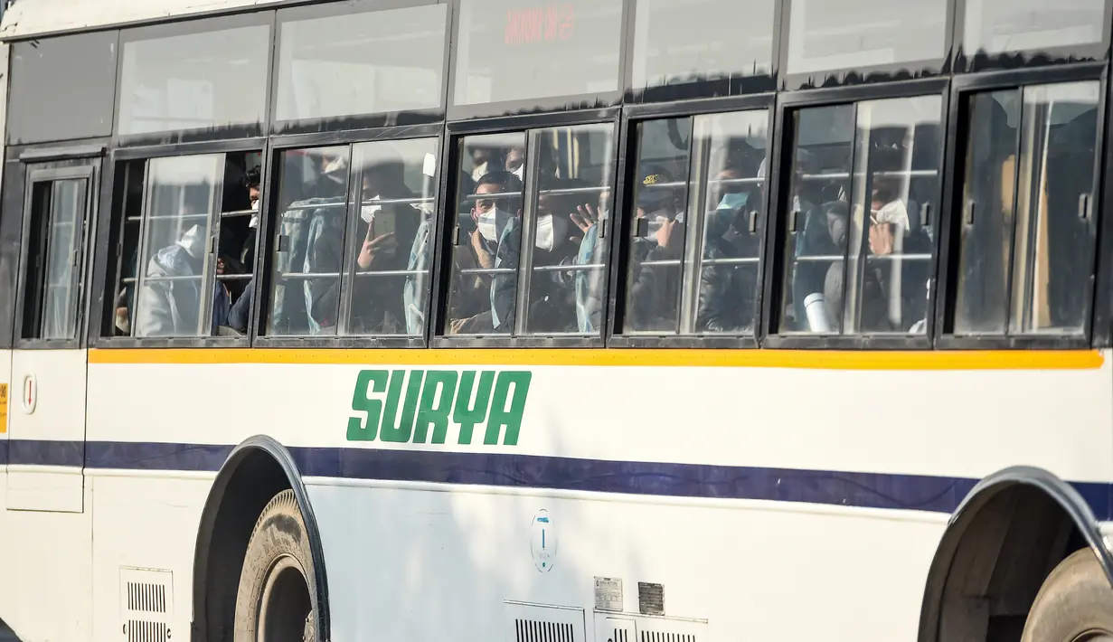 Warga negara India diangkut dengan bus keluar dari Bandara Internasional Indira Gandhi setelah dievakuasi dari kota Wuhan di China, di New Delhi (1/2/2020). India mengevakuasi sekitar 250 warganya dari Wuhan, kota di Hubei yang merupakan pusat wabah virus corona. (AFP/Money Sharma)
