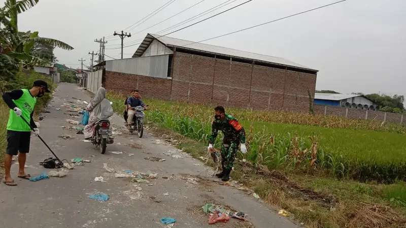 Serka Mashudi dan warga membersihkan sampah yang dibuang di tengah jalan raya, Rabu 19/5/2021. (Foto: Liputan6.com/Kusfitria Marstyasih)