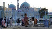 Seorang anak berpose untuk difoto saat mengunjungi Hazrat-e-Ali atau Masjid Biru di Mazar-e-Sharif, Afghanistan, Rabu (7/7/2021). Masjid Biru adalah tempat yang diminati orang-orang untuk menikmati ketenangan dari hiruk jalanan dan keramaian aktivitas pasar. (AP Photo/Rahmat Gul)