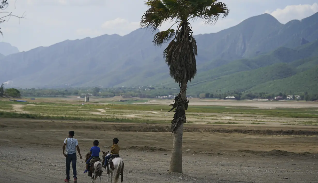 Anak-anak menunggang kuda di tepi pantai di Bendungan Boca yang memasok air ke kota utara Monterrey, di Santiago, Meksiko (9/7/2022). Perencanaan yang buruk, dan penggunaan air yang tinggi telah menyebabkan tiga bendungan yang membantu memasok kota mengering. (AP Photo/Fernando Llano)