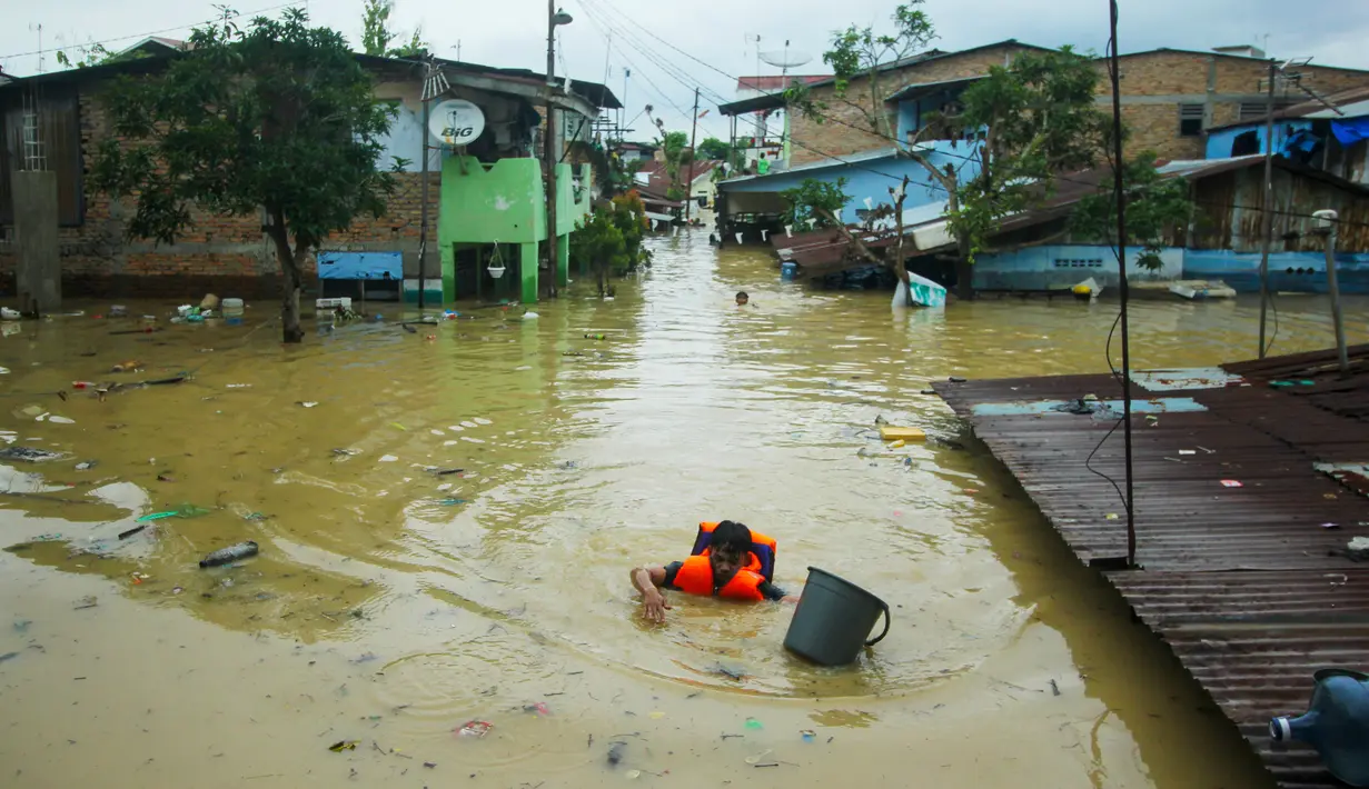 Seorang penyelamat mengarungi air banjir akibat hujan lebat semalam di Medan, Sumatera Utara (4/12/2020). Ketinggian air mulai 50 Cem hingga 1 meter lebih. (AFP/Rahmad Suryadi)