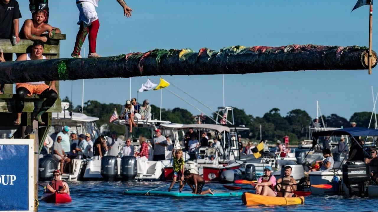 Peserta berjalan di tiang yang licin saat berkompetisi dalam Kontes Tiang Berminyak ke-94 dalam Perayaan Santo Petrus di Pantai Pavillion di Gloucester, Massachusetts, pada tanggal 28 Juni 2024. Foto: JOSEPH PREZIOSO / AFP<br>