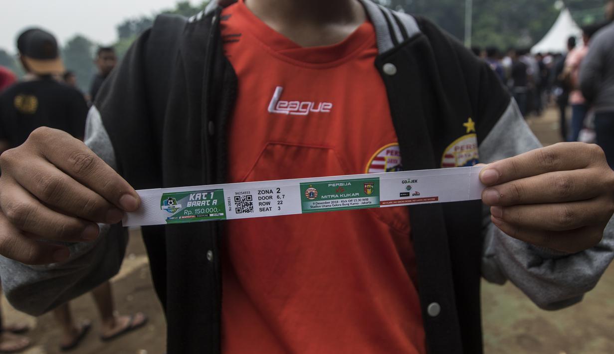 Suporter Persija Jakarta, The Jakmania, menunjukan tiket usai antri untuk menukar tiket di Lapangan Blok S, Jakarta, Minggu (9/12). Persija akan menjalani laga penentuan gelar juara melawan Mitra Kukar. (Bola.com/Vitalis Yogi Trisna)