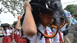 Sejumlah siswi SD menggunakan tas sekolah mereka untuk melindungi diri selama latihan tsunami di Tanjung Benoa dekat Denpasar di pulau resor Bali (15/8). (AFP Photo/ Sonny Tumbelaka)