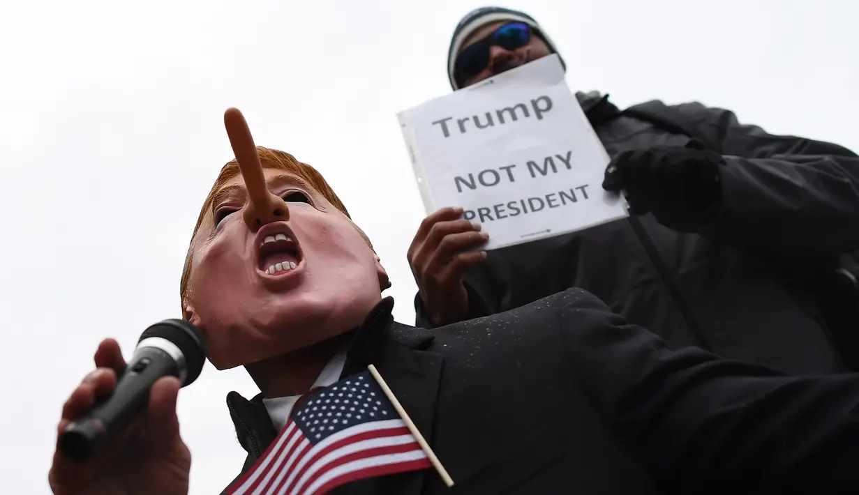 Demonstran bertopeng mirip Trump dengan hidung dipanjangkan menggelar aksi jelang pelantikan Donald Trump sebagai Presiden AS di Washington DC, Jumat (20/1). (AFP PHOTO / Jewel SAMAD)