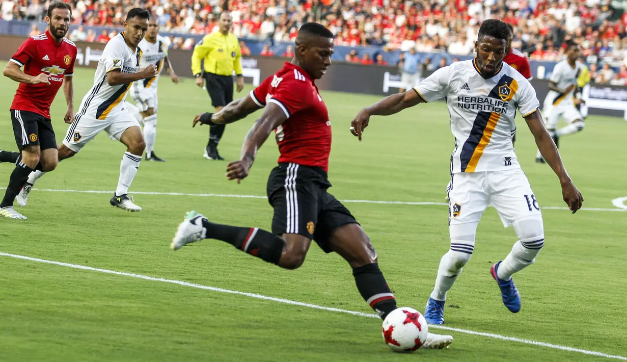 Pemain Manchester United, Antonio Valencia (kiri) mencoba melewati adanngan pemain LA Galaxy pada laga persahabatan di StubHub Center, California, Sabtu (15/7/2017). MU menang 5-2. (AFP/Ringo Chiu)